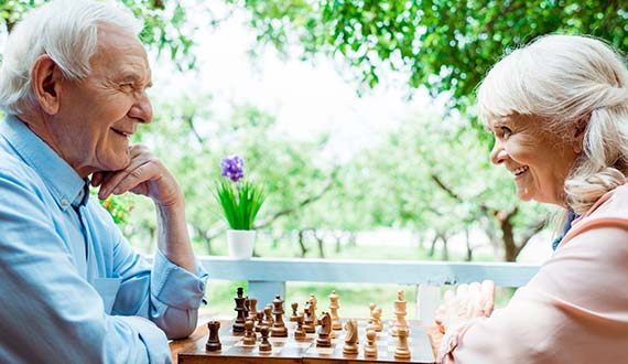 senior couple playing chess outdoors