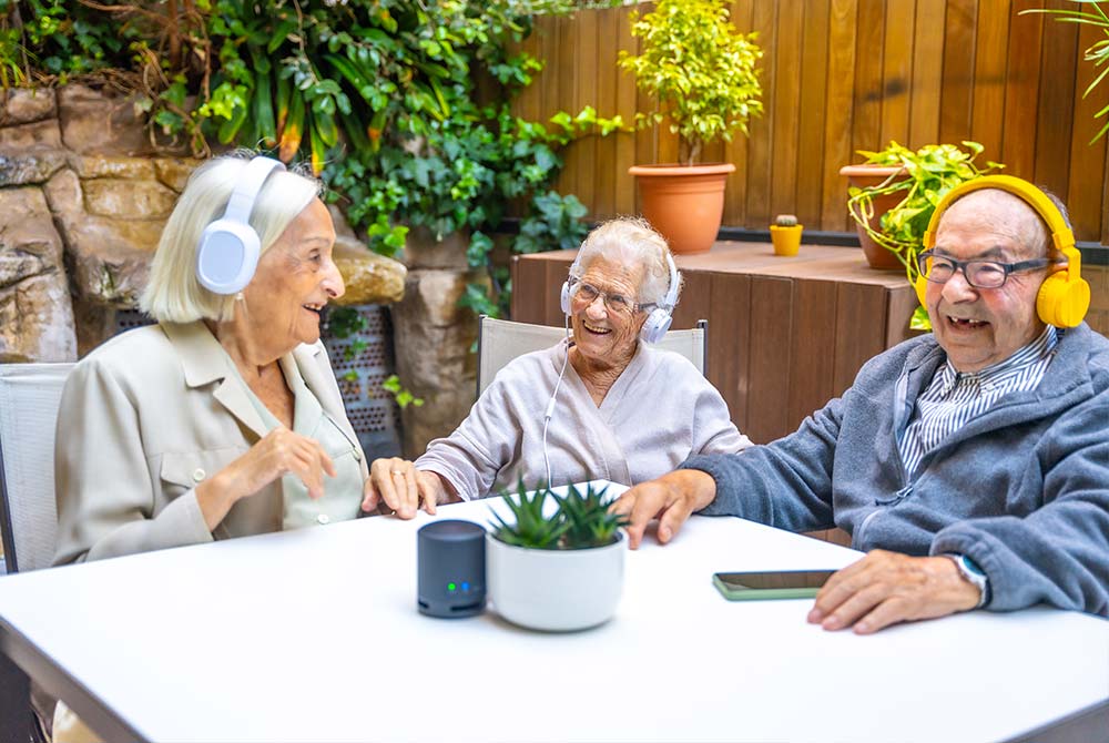 group of seniors outside listening to music on headphones and laughing